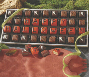 Happy Halloween petits fours decorated with chocolate and orange icing, white ghost faces and orange stripes.