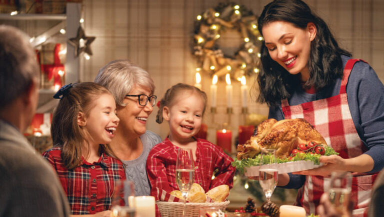 Family gathering around the dinner table with a turkey at holiday time