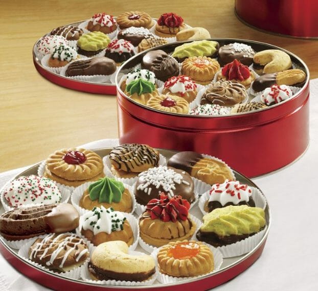 A decorative variety of holiday cookies displayed in a red tin and on two red tin lids.
