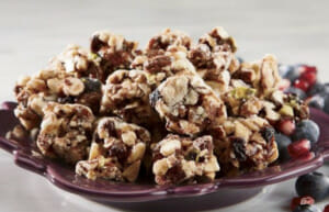 Blueberry crunch bite size granola and blueberries pieces served on a purple plate.