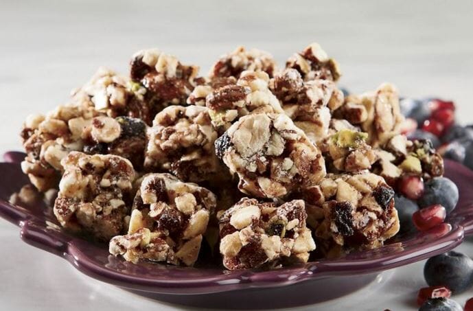 Blueberry crunch bite size granola and blueberries pieces served on a purple plate.