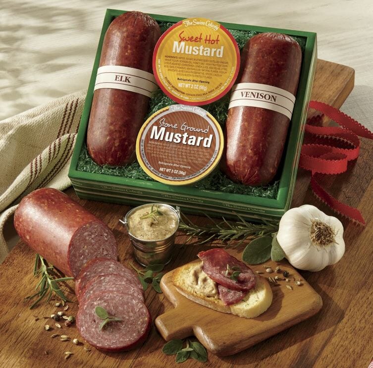 Elk and venison sausage gift box with sliced sausage, dip and a cutting board on the side.