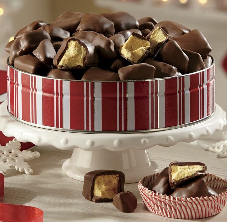 Chocolate covered honeycomb candy in a red and white striped tin, with cut samples to show the texture.