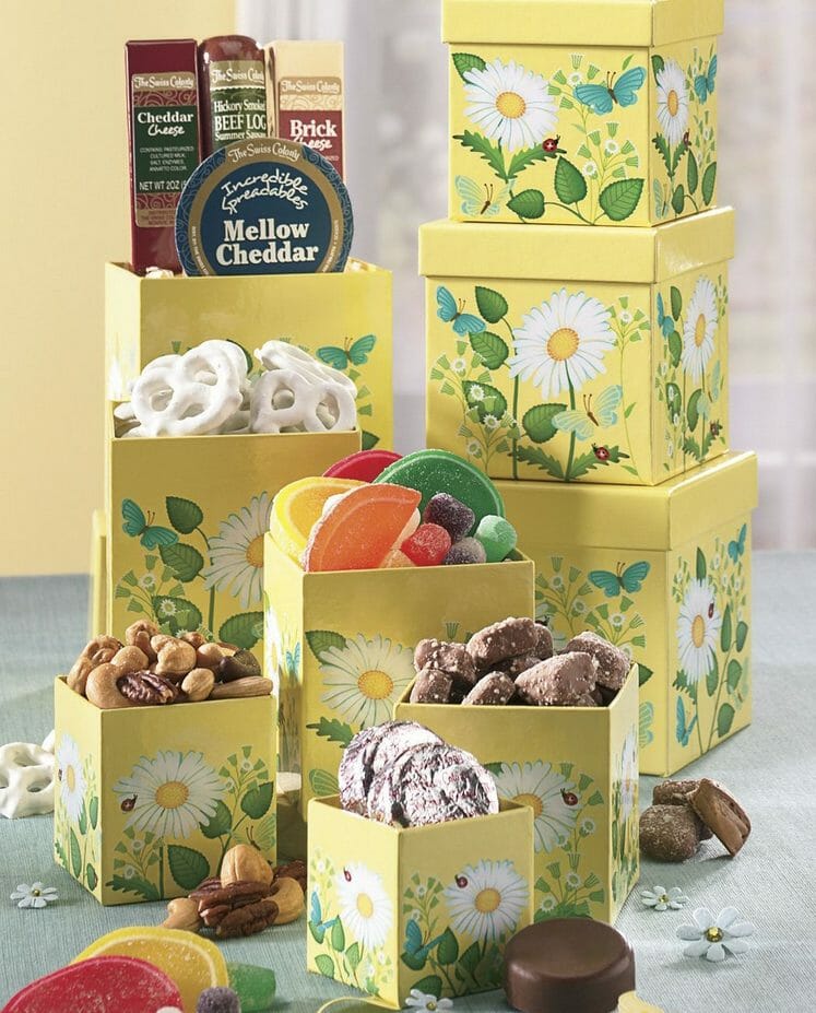 Yellow spring flower towers with boxes displaying a beef log, cheese, chocolates, mixed nuts, candies and more.