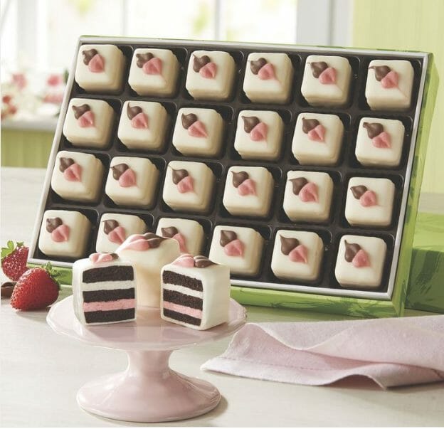 Neapolitan petits fours in a spring green box with a small pedestal plate displaying cut samples to show the layers.