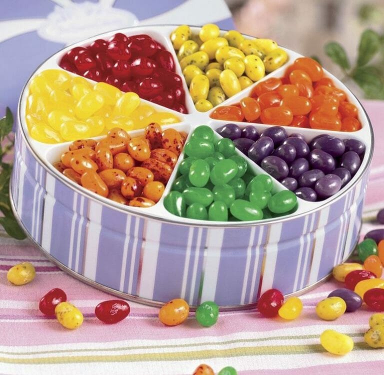 Red, orange, yellow, green and purple fruity jelly belly jelly beans in a lavender and white striped tin.