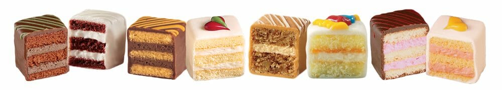 Eight varieties of petits fours in a row, cut in half to display the layers.