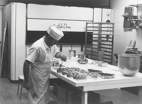 Pre-1970's pastry chef putting final touches on fruitcake.