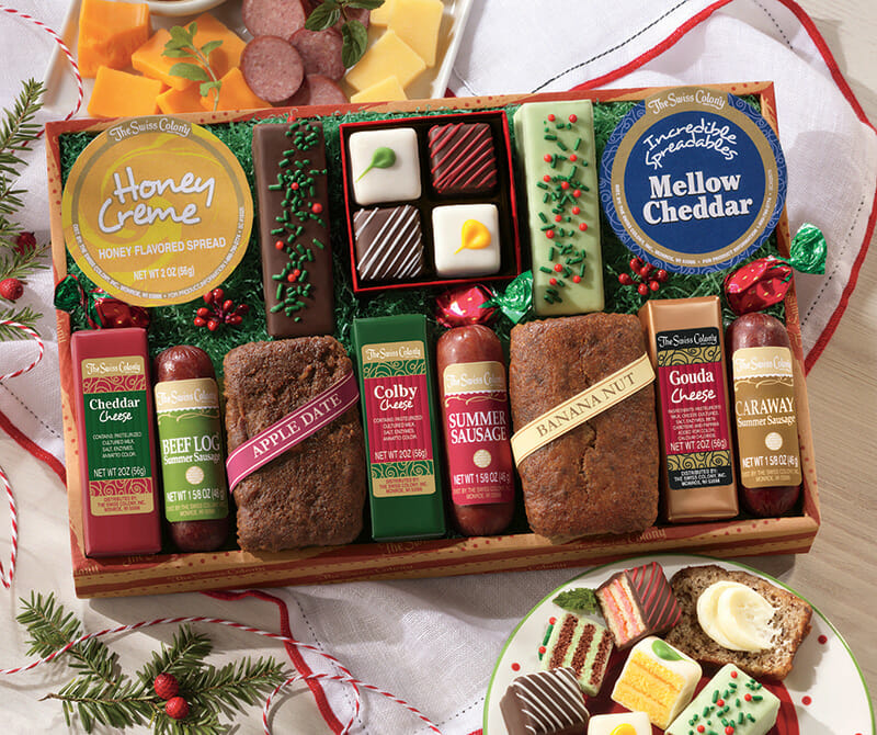 Food gift box with sausage, cheese, bread, petits fours, tortes and cheese spread with a side plate of samples.