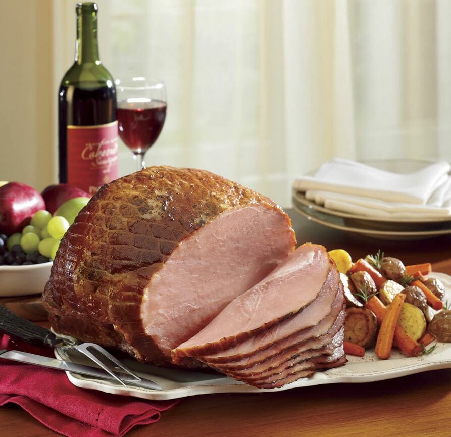 Boneless spiral sliced ham, mixed veggies and potatoes served with a glass of red wine and fresh grapes.