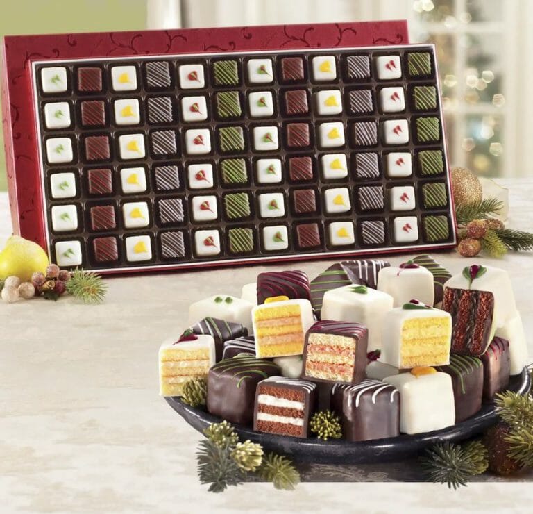Christmas Petits Fours displayed in a gift box with a plate of sliced Petits Fours showing many flavors and layers. 