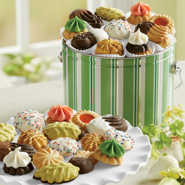 A green- and white-striped tin pail filled with a variety of hand-decorated cookies