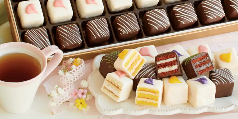 Assorted Petits Fours on a white plate with a cup of tea.