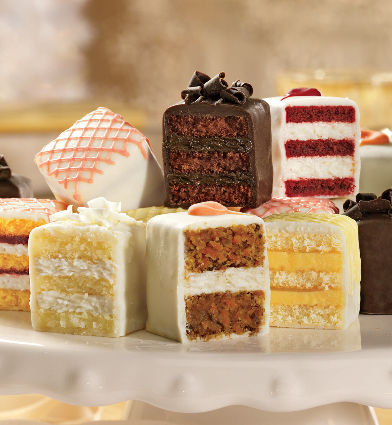 A box of 24 Petits Fours in six flavors coated with chocolate or white confection and decorated with chocolate, coconut, or icing designs