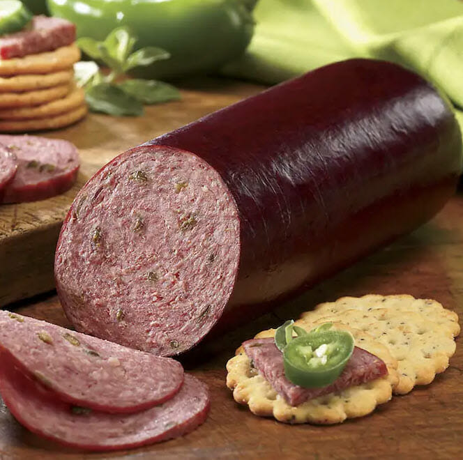 Partially sliced jalapeno summer sausage with crackers.