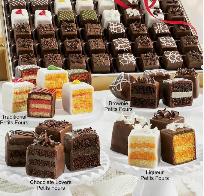 large petits fours gift assortment with traditional, brownie, chocolate lover, and liqueur flavor petits fours on white plates in front